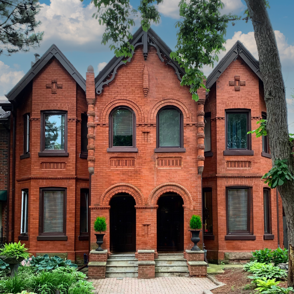 Photograph of a typical Toronto Bay-and-Gable home, showcasing its distinctive narrow structure with a prominent bay window and steep gable roof, set against a backdrop of tree-lined streets in a historic Toronto neighborhood.